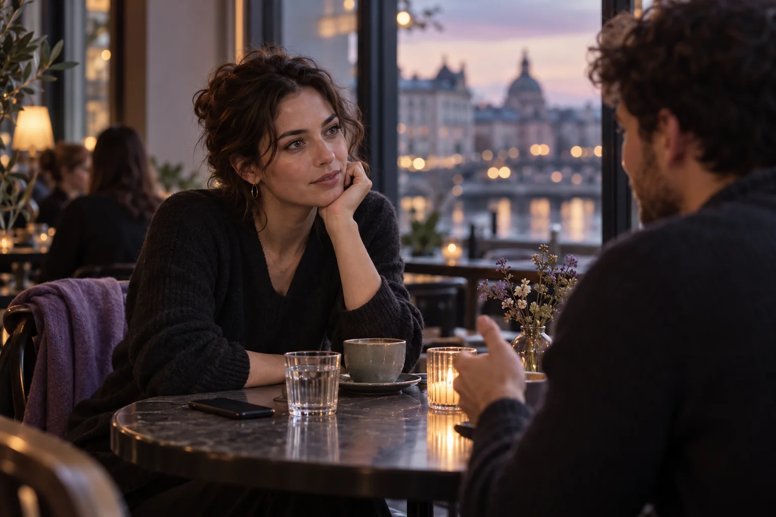 Two people share a thoughtful conversation at a café table while a phone rests face down nearby.
