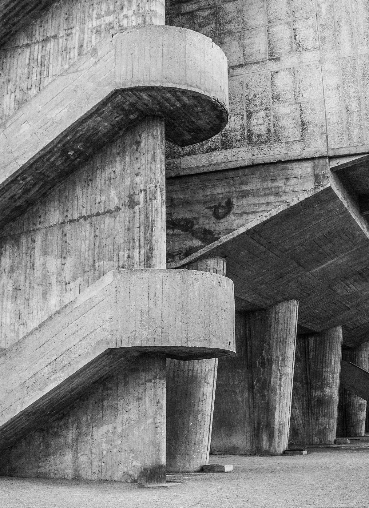 A black and white concrete staircase turns through a sculptural brutalist building.