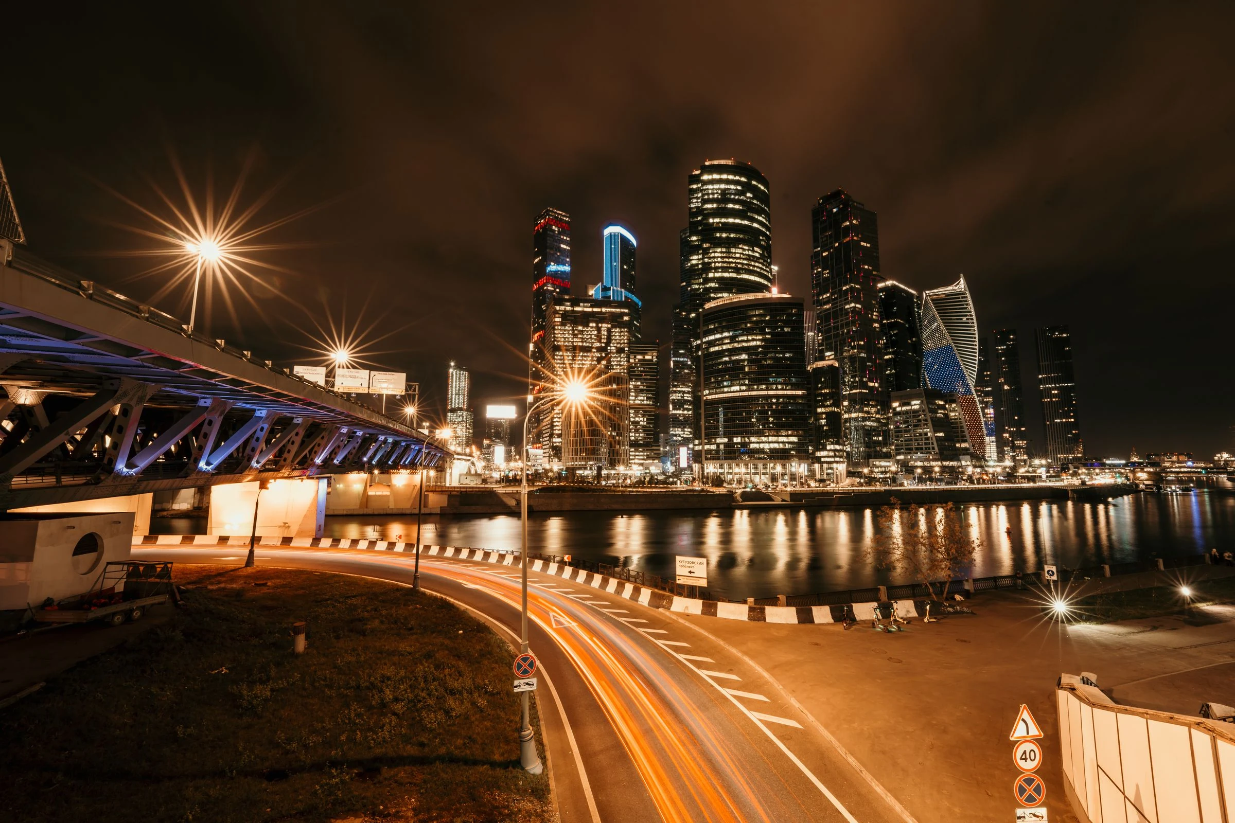 Light trails crossing a city riverfront at night.