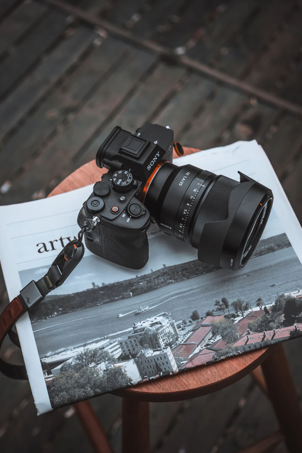 A digital camera rests on a printed photograph of a city beside a newspaper.