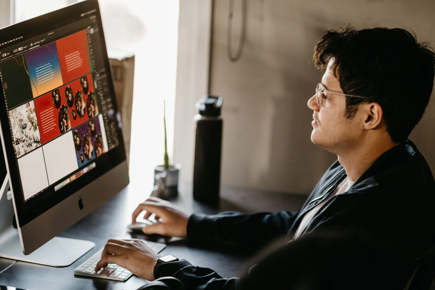 A designer studies a visual workspace on a large desktop display.