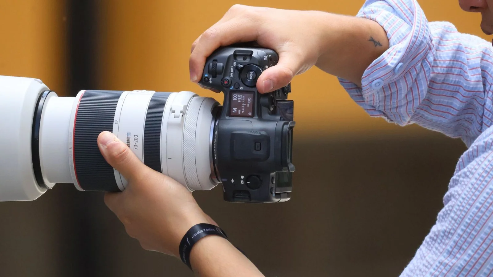 A photographer holds a camera with a long lens.