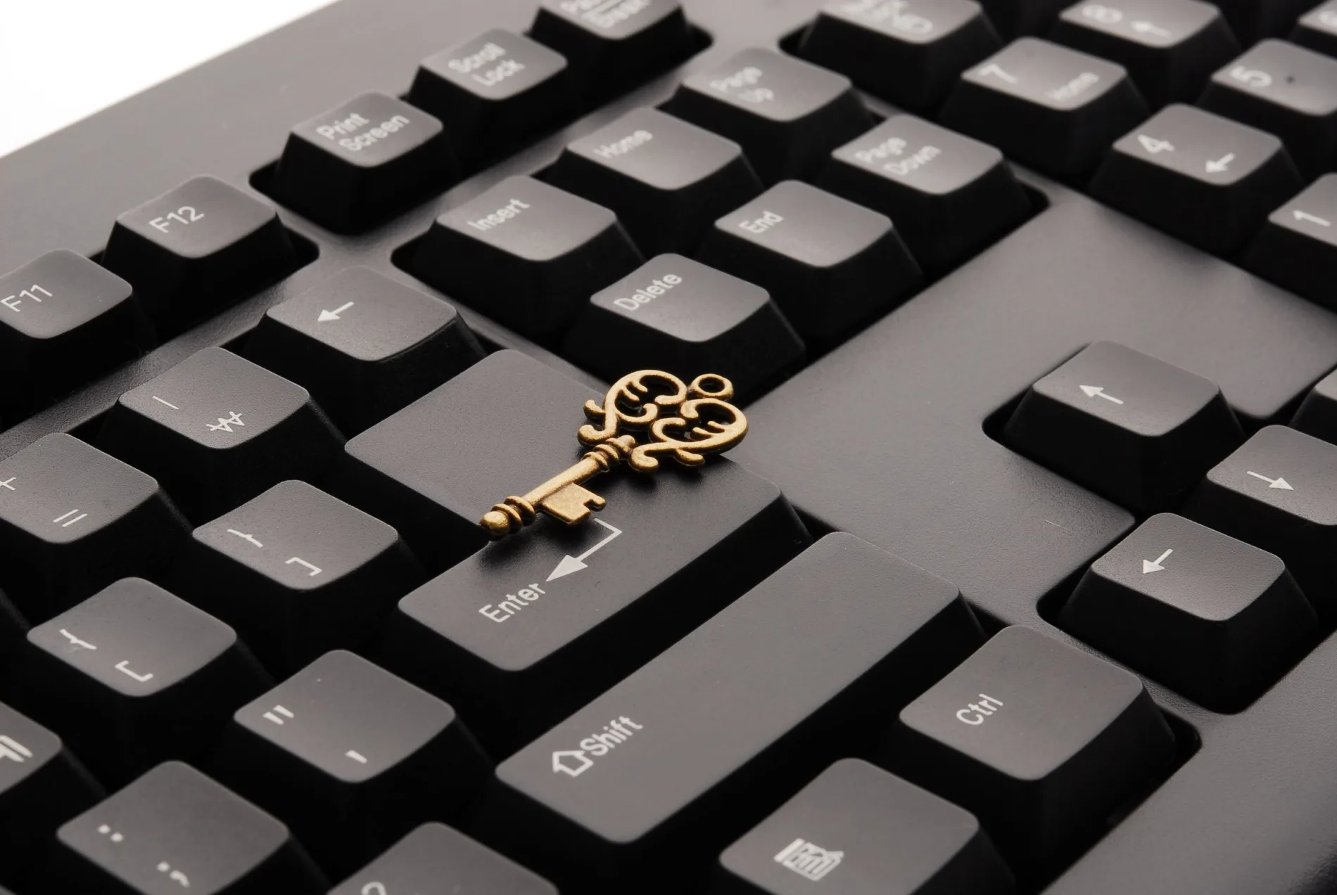 An ornate key rests across the keys of a computer keyboard.