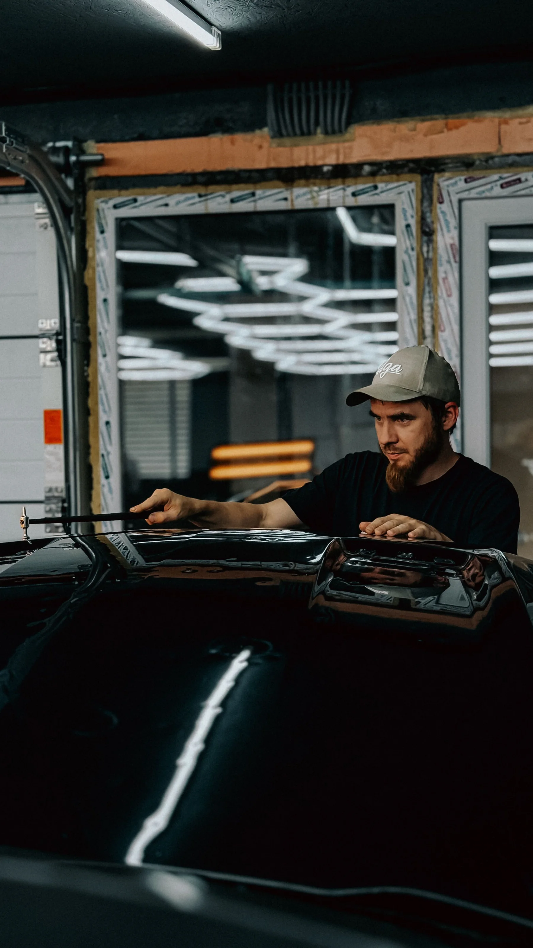 A mechanic carefully works on the surface of a car in a workshop.